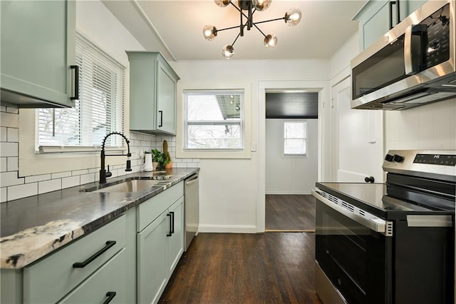 4412 N Jackson Ave, Kansas City, MO 64117 - kitchen featuring backsplash, sink, appliances with stainless steel finishes, a notable chandelier, and dark hardwood / wood-style flooring