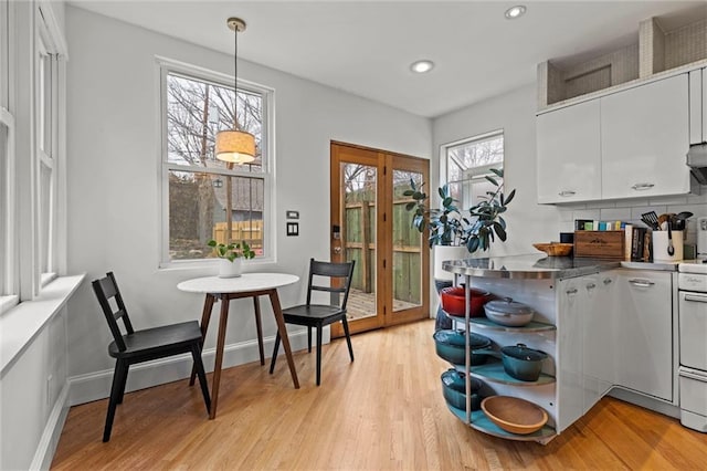 kitchen featuring decorative backsplash, light hardwood / wood-style floors, white cabinetry, and hanging light fixtures