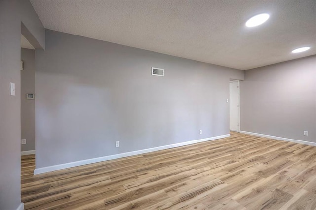 unfurnished room with a textured ceiling and light hardwood / wood-style flooring