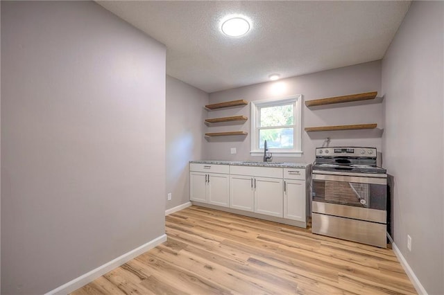 kitchen featuring light wood-type flooring, a textured ceiling, sink, white cabinets, and stainless steel electric range