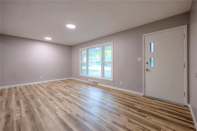 entrance foyer with light hardwood / wood-style floors and a textured ceiling