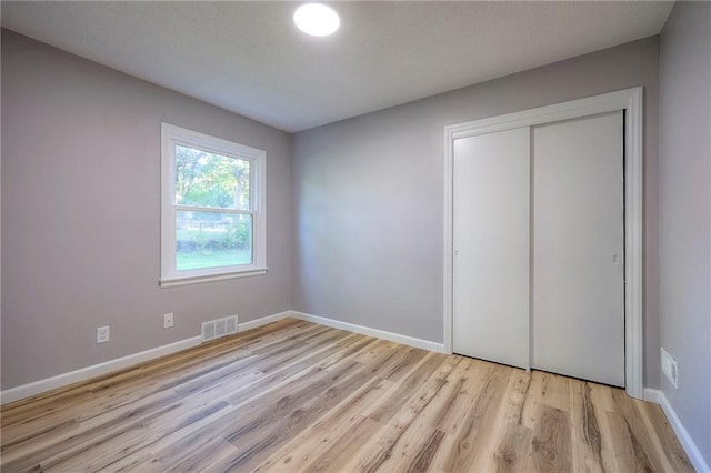 unfurnished bedroom with a closet and light hardwood / wood-style floors