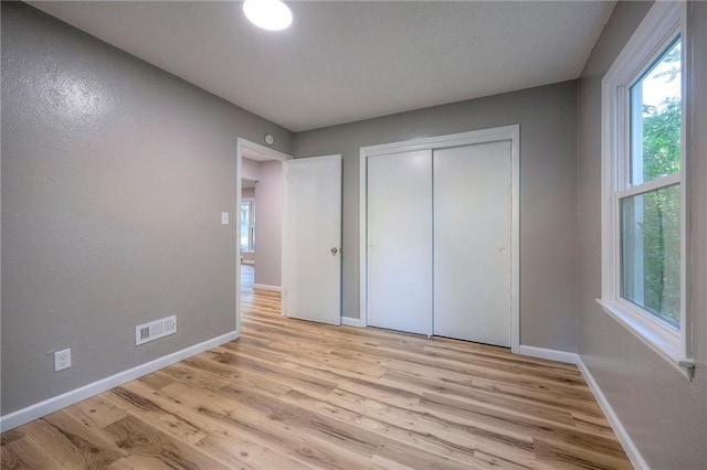 unfurnished bedroom with light wood-type flooring and a closet