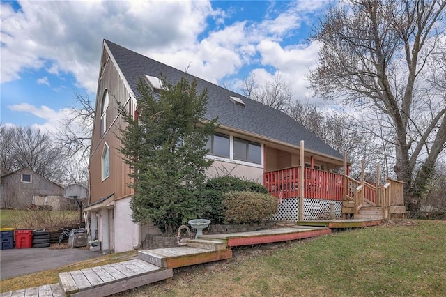 back of property featuring a lawn, a garage, and a wooden deck