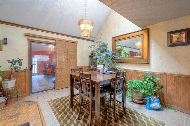 dining space featuring a textured ceiling, an inviting chandelier, vaulted ceiling, and wooden walls