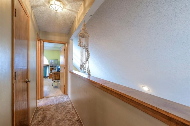 hall featuring light carpet and a textured ceiling