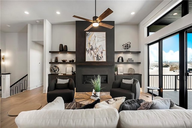 16781 S Fellows St, Olathe, KS 66062 - living room featuring wood finished floors, a ceiling fan, a glass covered fireplace, and recessed lighting