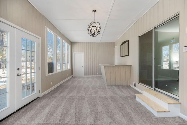 unfurnished sunroom featuring an inviting chandelier and french doors