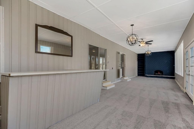 hallway with a notable chandelier and light colored carpet