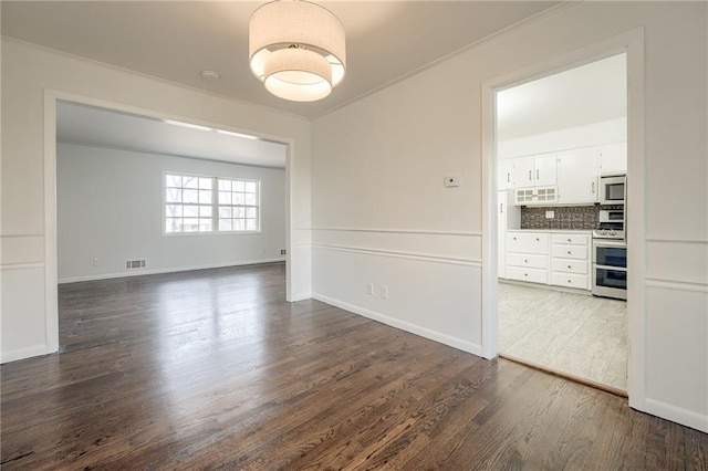 unfurnished dining area featuring crown molding and dark hardwood / wood-style floors