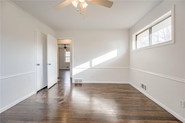 empty room featuring dark hardwood / wood-style flooring, plenty of natural light, and ceiling fan