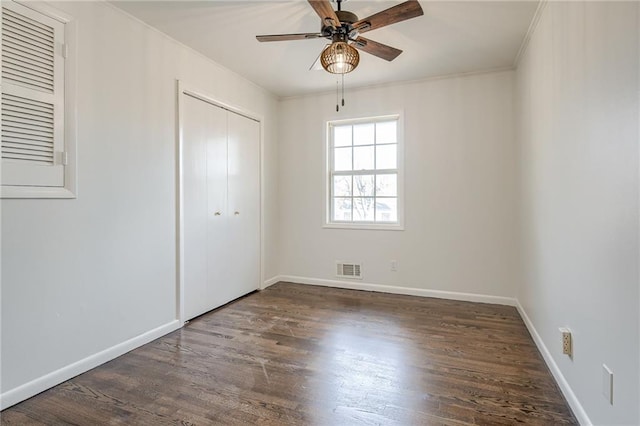 unfurnished bedroom with dark hardwood / wood-style flooring, a closet, ceiling fan, and crown molding