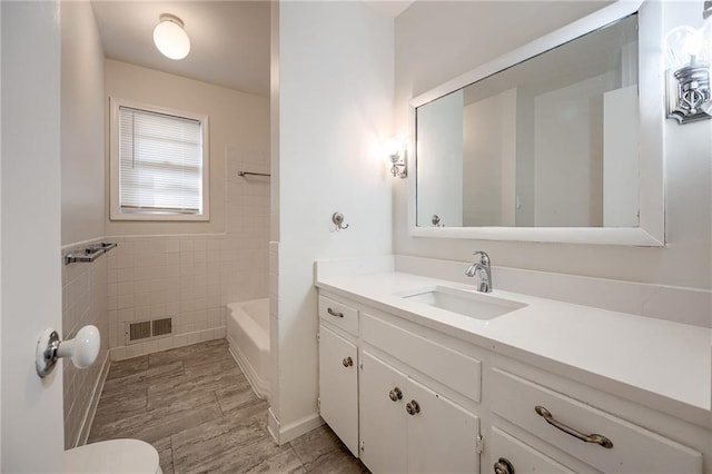 full bathroom featuring shower / bathtub combination, vanity, tile walls, and toilet