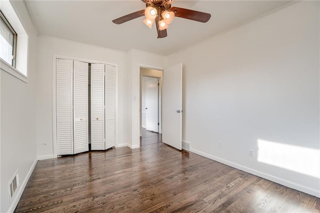 unfurnished bedroom with dark hardwood / wood-style flooring, a closet, ceiling fan, and crown molding