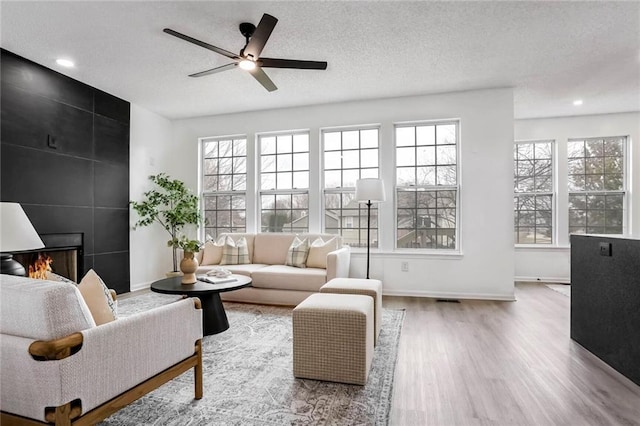 interior space with ceiling fan, a tile fireplace, and a wealth of natural light