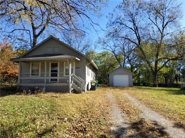 bungalow-style house featuring an outbuilding, covered porch, a front yard, and a garage