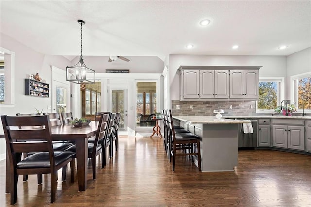 kitchen featuring dishwasher, light stone countertops, gray cabinetry, and decorative light fixtures