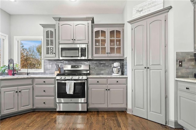 kitchen with dark wood-type flooring, sink, gray cabinetry, stainless steel appliances, and backsplash