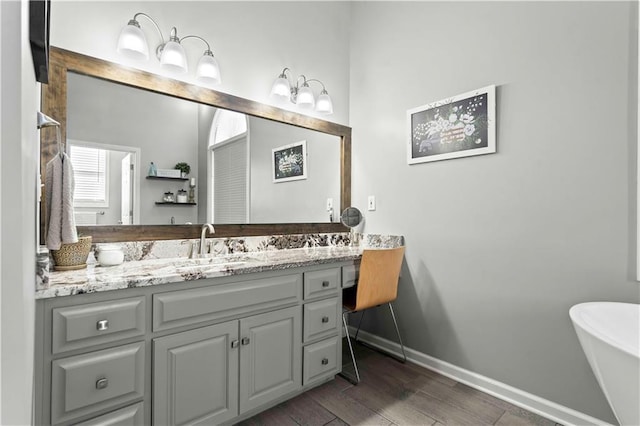 bathroom featuring vanity, wood-type flooring, and a bath