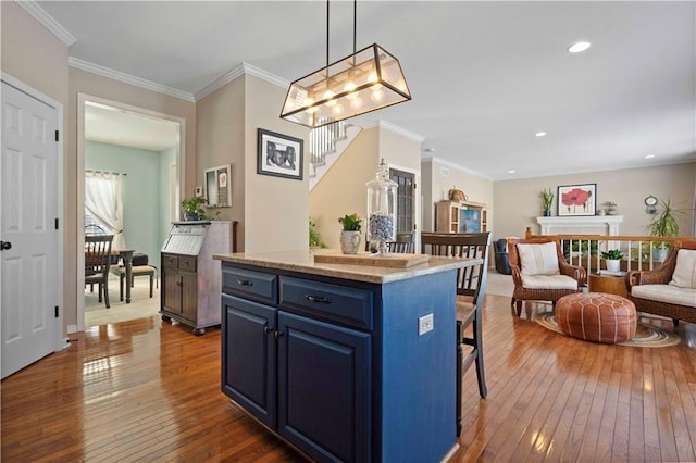 kitchen featuring hardwood / wood-style floors, a kitchen bar, hanging light fixtures, a center island, and blue cabinetry