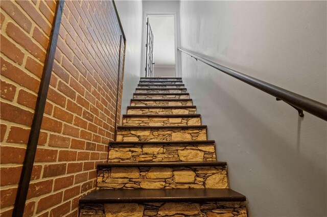 staircase featuring brick wall