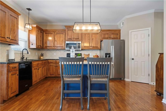 kitchen with pendant lighting, sink, a kitchen bar, stainless steel appliances, and a kitchen island