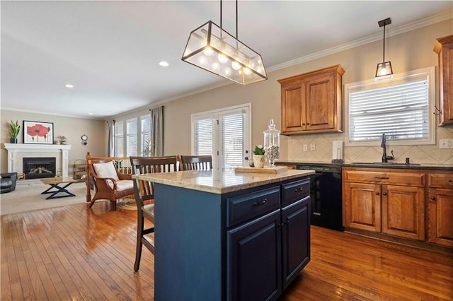 kitchen with a kitchen island, pendant lighting, dishwasher, sink, and dark stone countertops