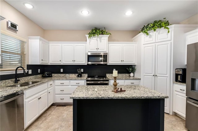 kitchen featuring appliances with stainless steel finishes, sink, white cabinetry, and a kitchen island