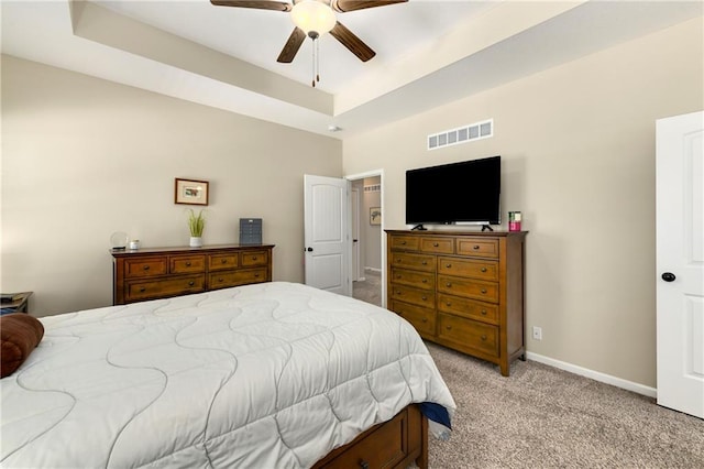 carpeted bedroom with ceiling fan and a tray ceiling