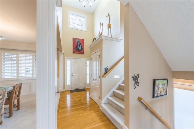 foyer entrance featuring a towering ceiling and light hardwood / wood-style flooring