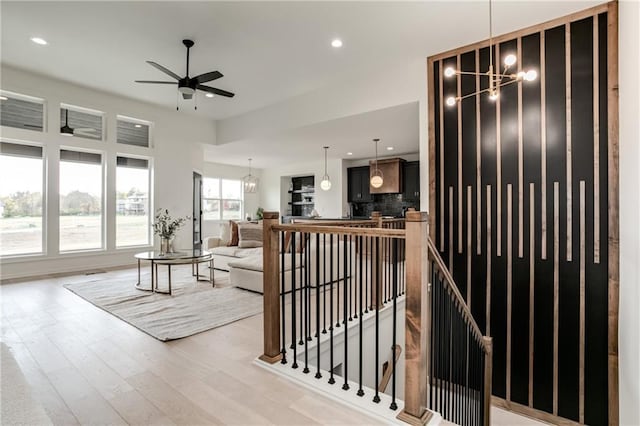 living room with light hardwood / wood-style floors and ceiling fan with notable chandelier