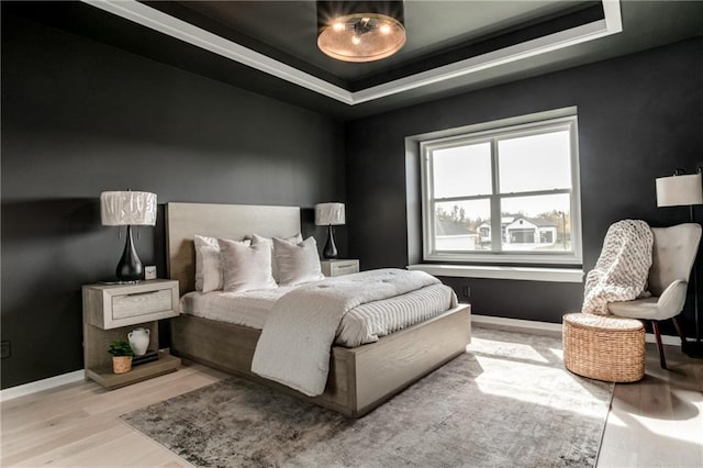 bedroom with a raised ceiling and light hardwood / wood-style flooring