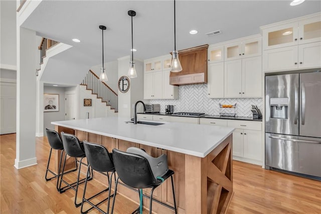 kitchen featuring white cabinetry, sink, pendant lighting, a center island with sink, and appliances with stainless steel finishes