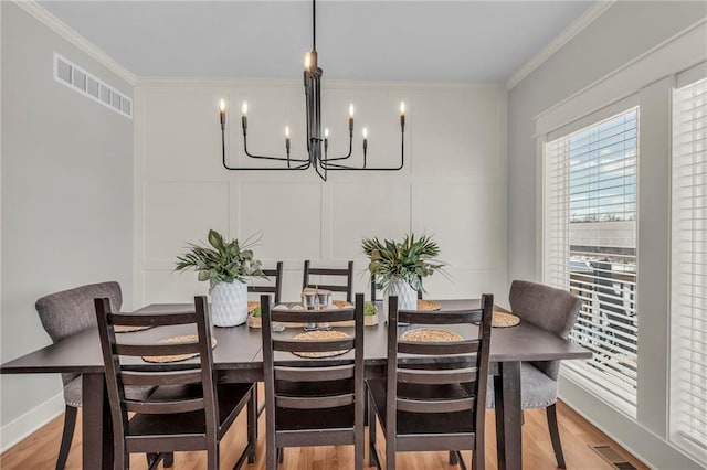 dining space featuring light hardwood / wood-style floors, crown molding, and a notable chandelier