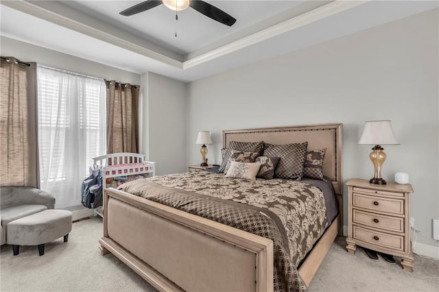 bedroom with a tray ceiling, ceiling fan, and light carpet