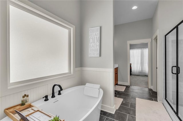 bathroom featuring wainscoting, a soaking tub, vanity, a shower stall, and recessed lighting