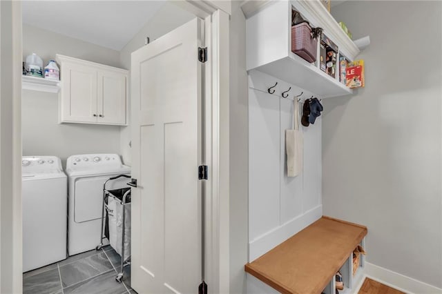 clothes washing area with washing machine and dryer, cabinet space, and baseboards