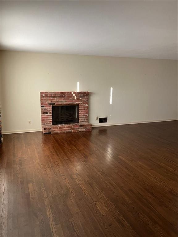 unfurnished living room featuring dark hardwood / wood-style floors and a brick fireplace