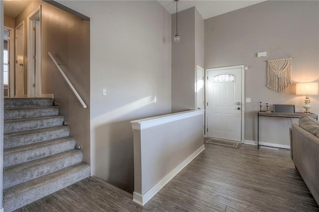 entryway with a towering ceiling and dark hardwood / wood-style flooring