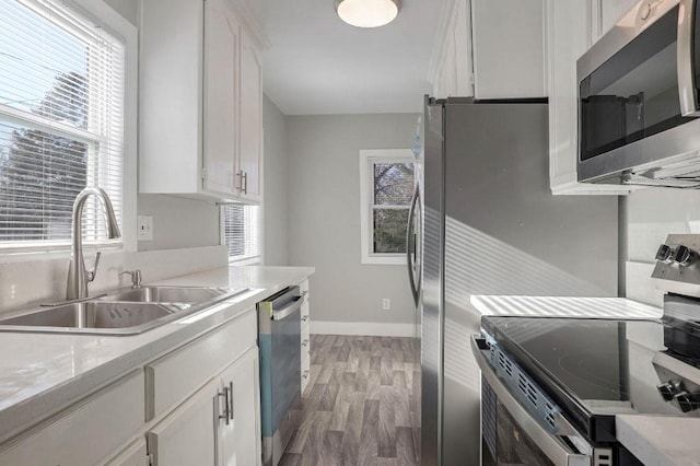 kitchen with hardwood / wood-style floors, sink, white cabinetry, and stainless steel appliances