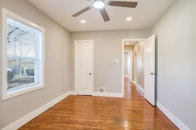 unfurnished bedroom with ceiling fan, light wood-type flooring, and multiple windows