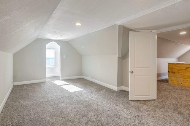 additional living space featuring carpet flooring, a textured ceiling, and vaulted ceiling