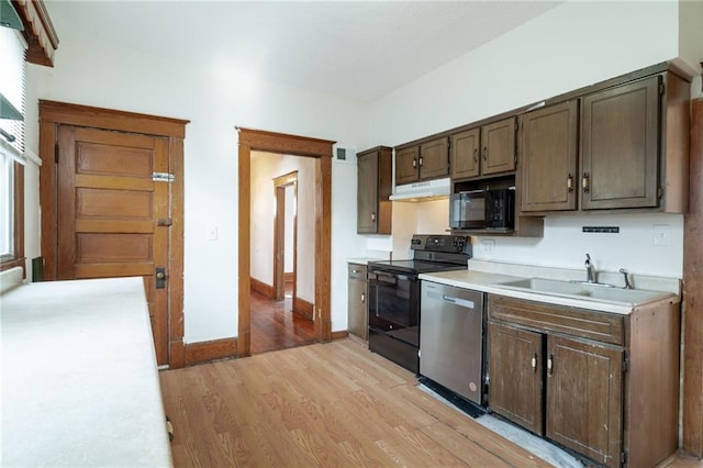 kitchen featuring black appliances, dark brown cabinets, light wood-type flooring, and sink