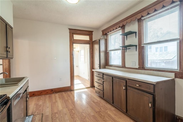 kitchen featuring sink, a textured ceiling, dark brown cabinets, light hardwood / wood-style floors, and stainless steel appliances