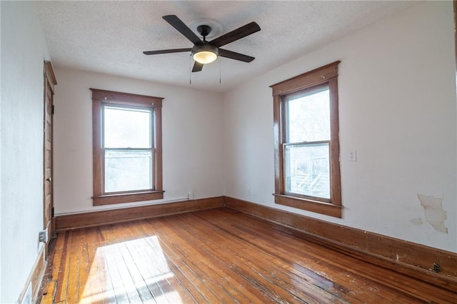 empty room featuring hardwood / wood-style floors, ceiling fan, a textured ceiling, and a wealth of natural light