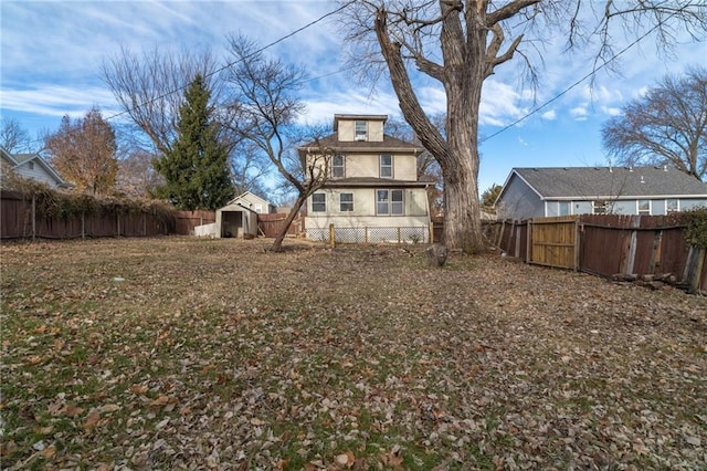 back of house with a storage shed