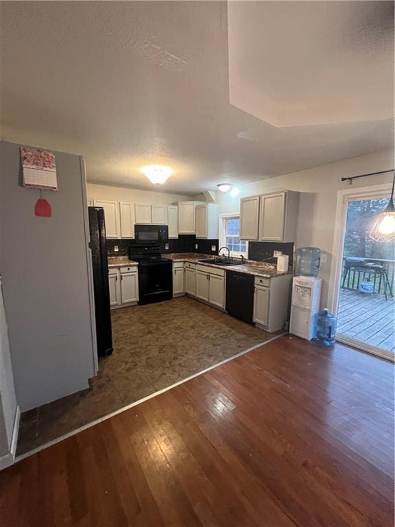 kitchen with black appliances, white cabinets, sink, decorative light fixtures, and dark hardwood / wood-style flooring