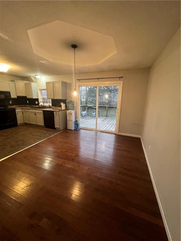 interior space with a tray ceiling, sink, and dark wood-type flooring