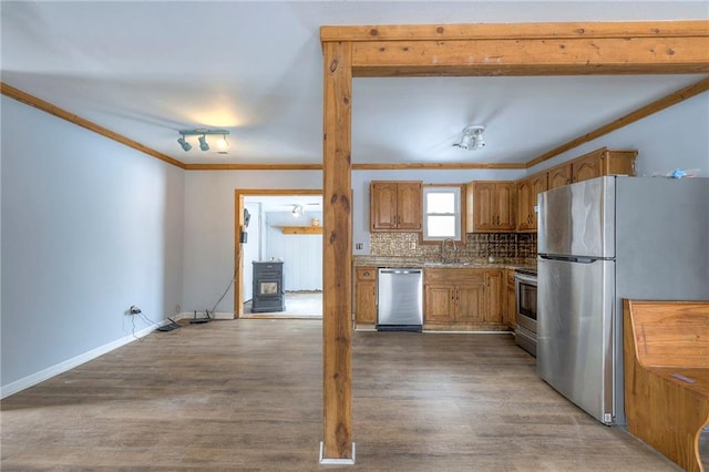 kitchen featuring sink, backsplash, hardwood / wood-style floors, appliances with stainless steel finishes, and ornamental molding