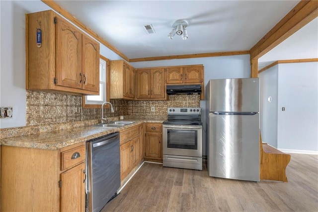 kitchen featuring decorative backsplash, light wood-type flooring, ornamental molding, stainless steel appliances, and sink